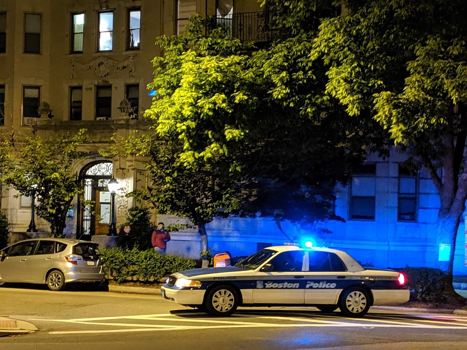 A police cruiser at night with emergency lights on