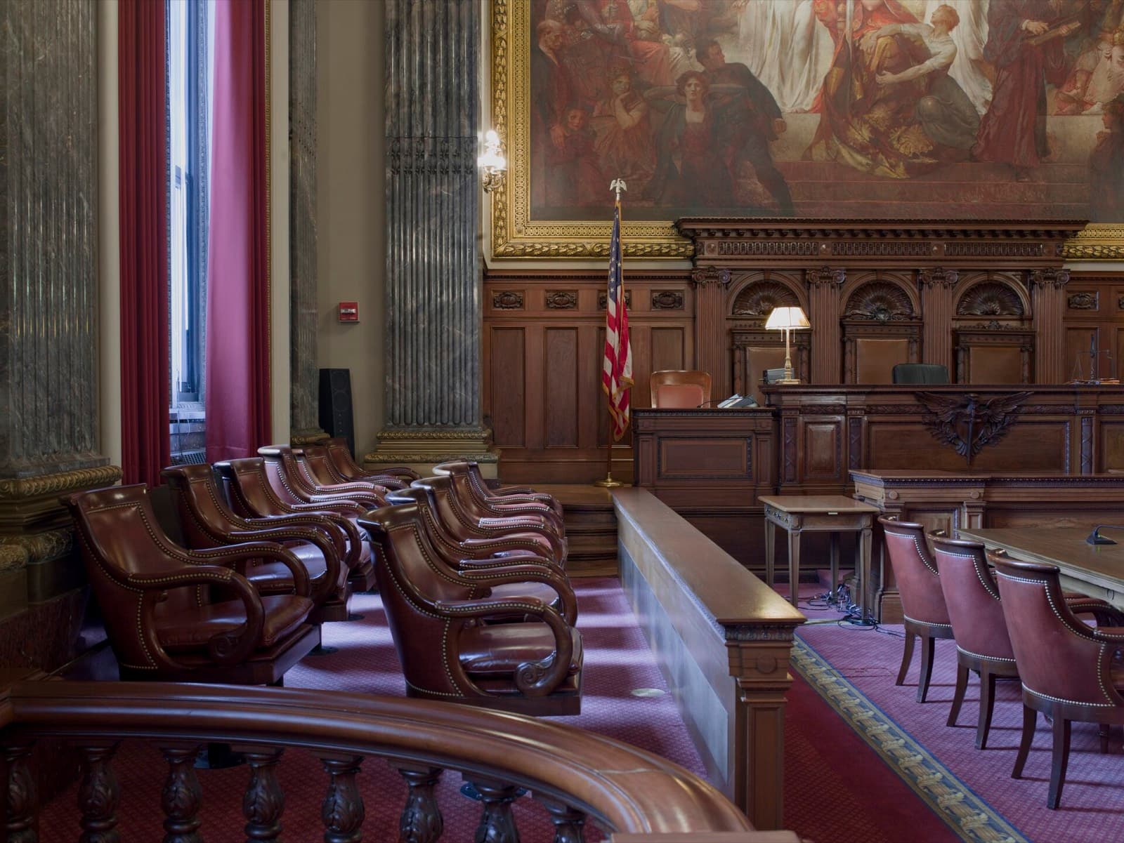A historic courtroom with wooden benches and tall windows
